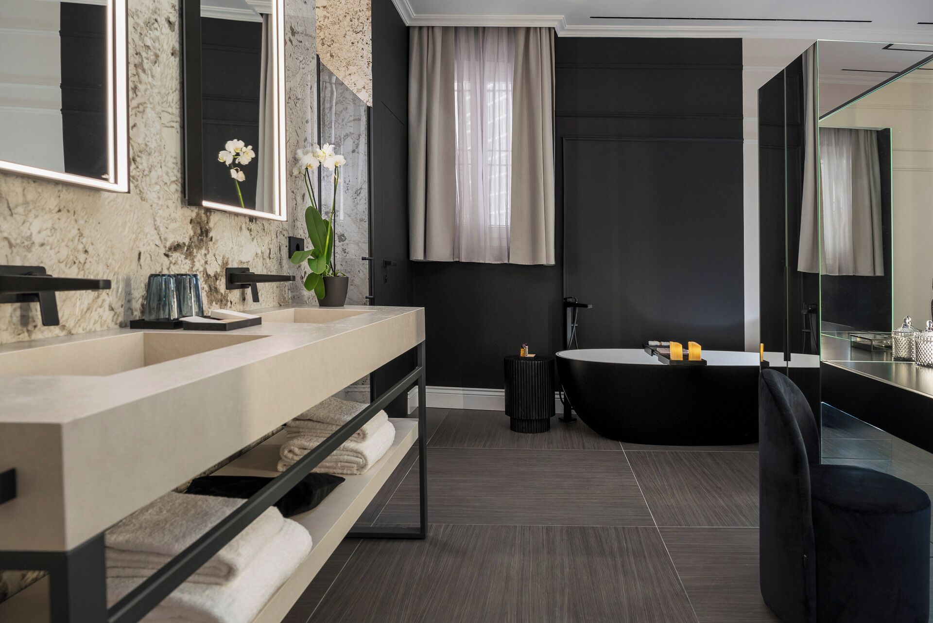 A modern bathroom with a double sink vanity, a large mirror, a bathtub, and a potted orchid.