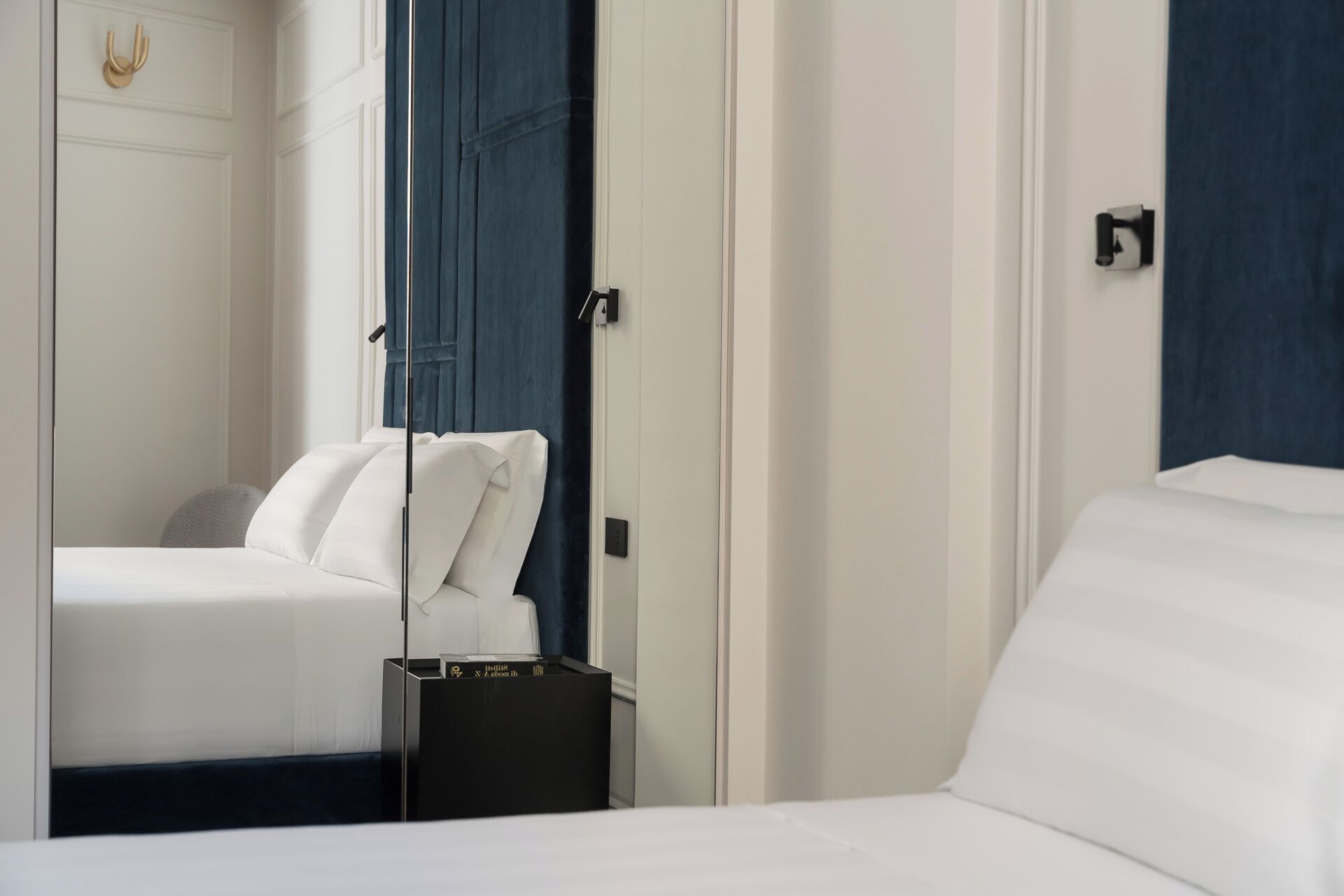 Ein Hotelzimmer mit Bett, Nachttisch und einem Spiegel, der den Raum widerspiegelt.