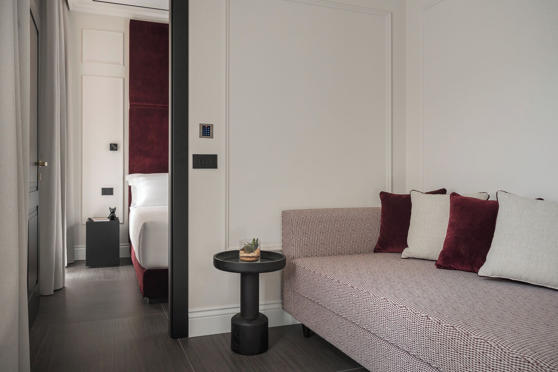 Une chambre d’hôtel moderne, équipée d’un lit, d’une petite table de chevet et d’une porte donnant sur une autre pièce.