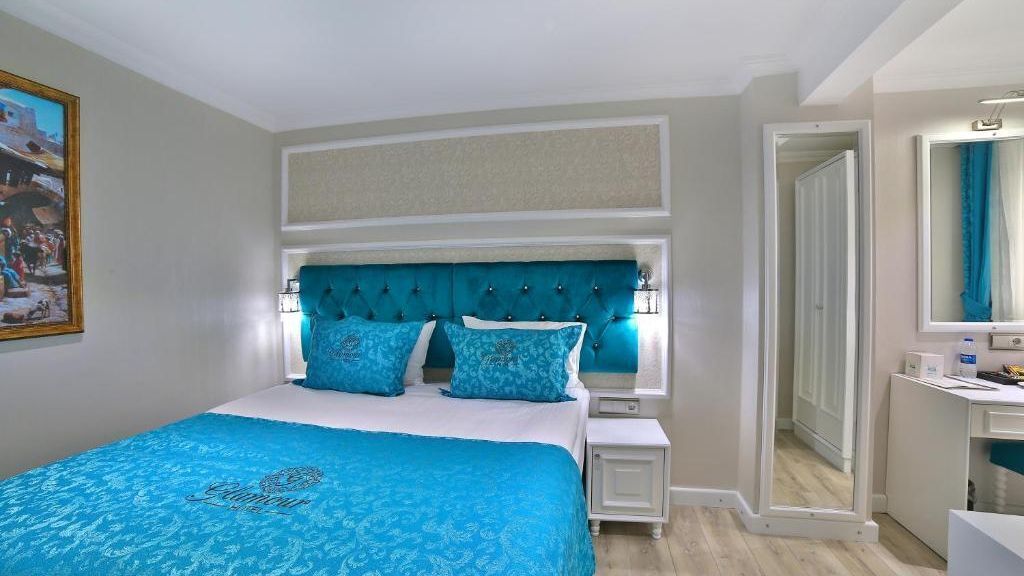 Ein Schlafzimmer mit einem Bett, Nachttischen, einem Spiegel und einer Tür zu einem weiteren Raum.