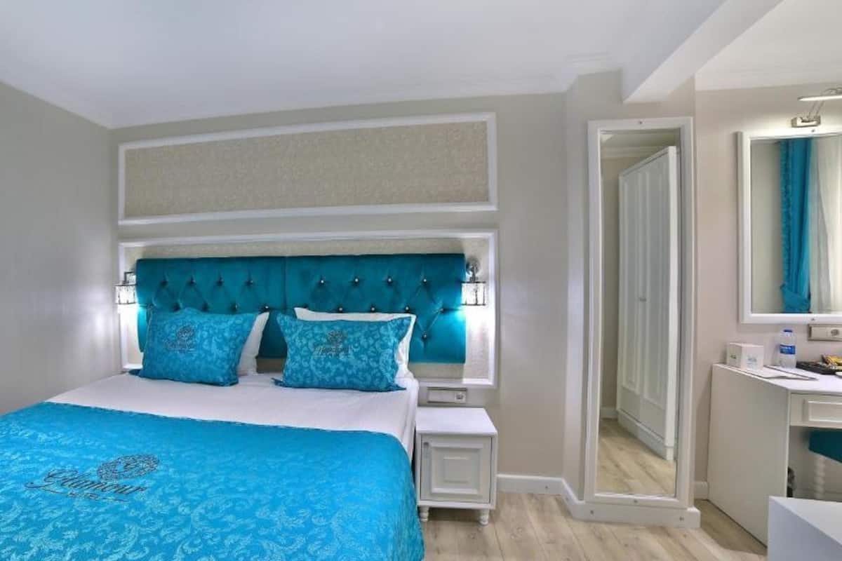 Quarto com cama, mesas de cabeceira, um espelho e porta para outro espaço.