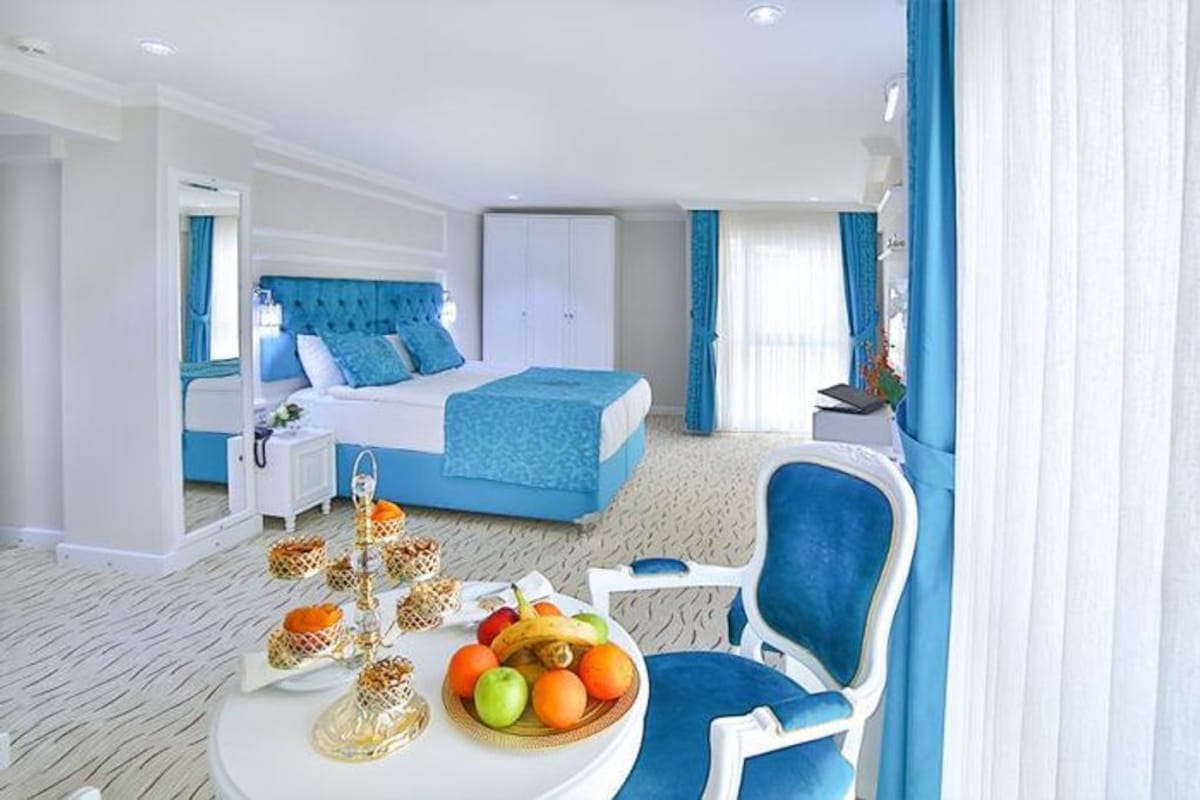 Une chambre d’hôtel avec un lit, une table à manger avec des fruits, une chaise et une armoire.