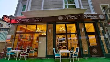 Ein Hotelgebäude mit einem Café namens 'Nargile Cafe' und der Beschilderung 'Glamour Hotel'.