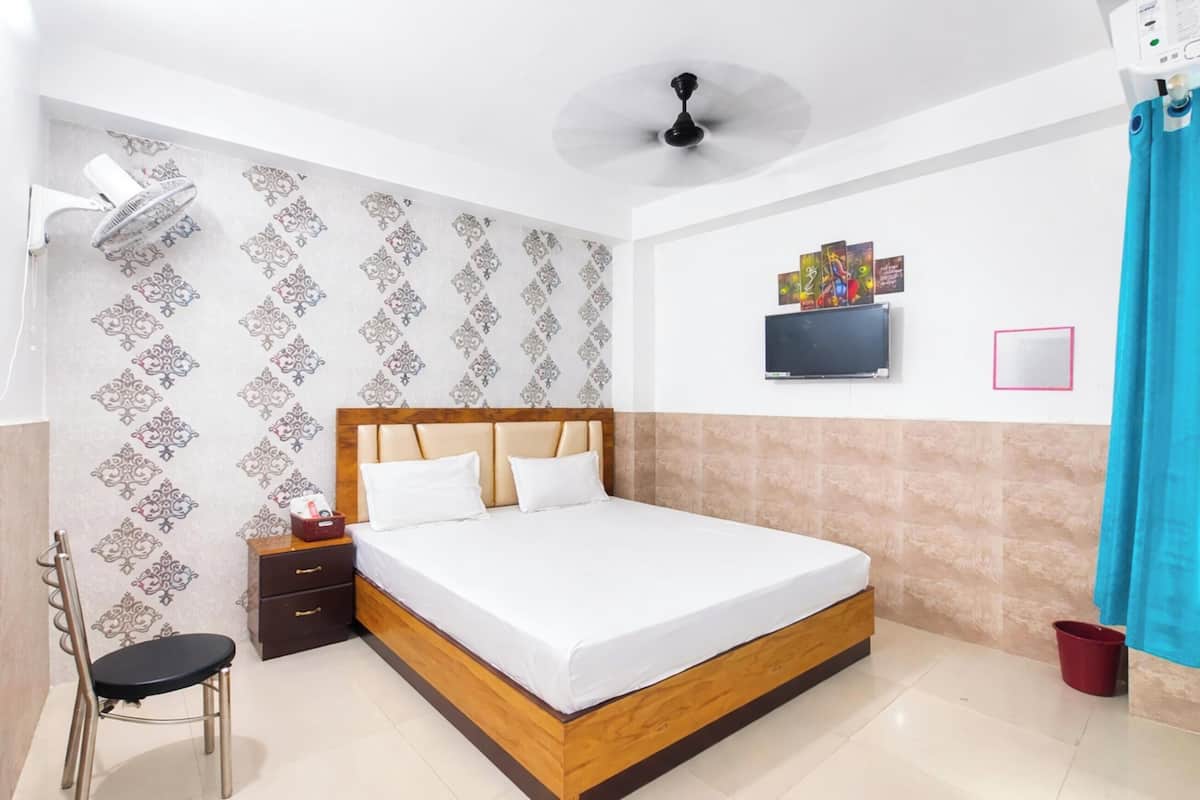 A bedroom with a bed, a chair, a nightstand, a TV, and a ceiling fan.