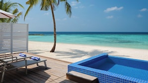 Een houten terras met lounge stoelen en een klein zwembad met blauwe tegels.