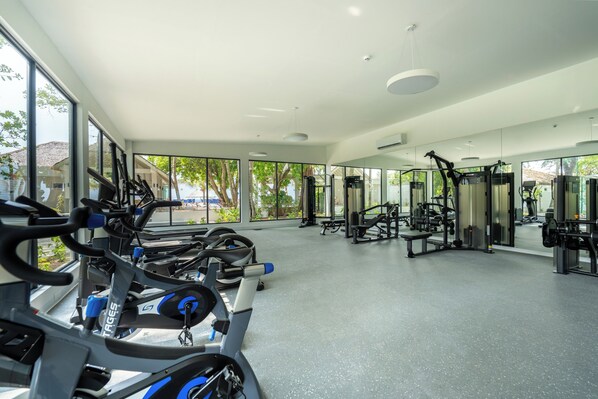 Un gimnasio con equipo de cardio, máquinas de pesas y espejos.