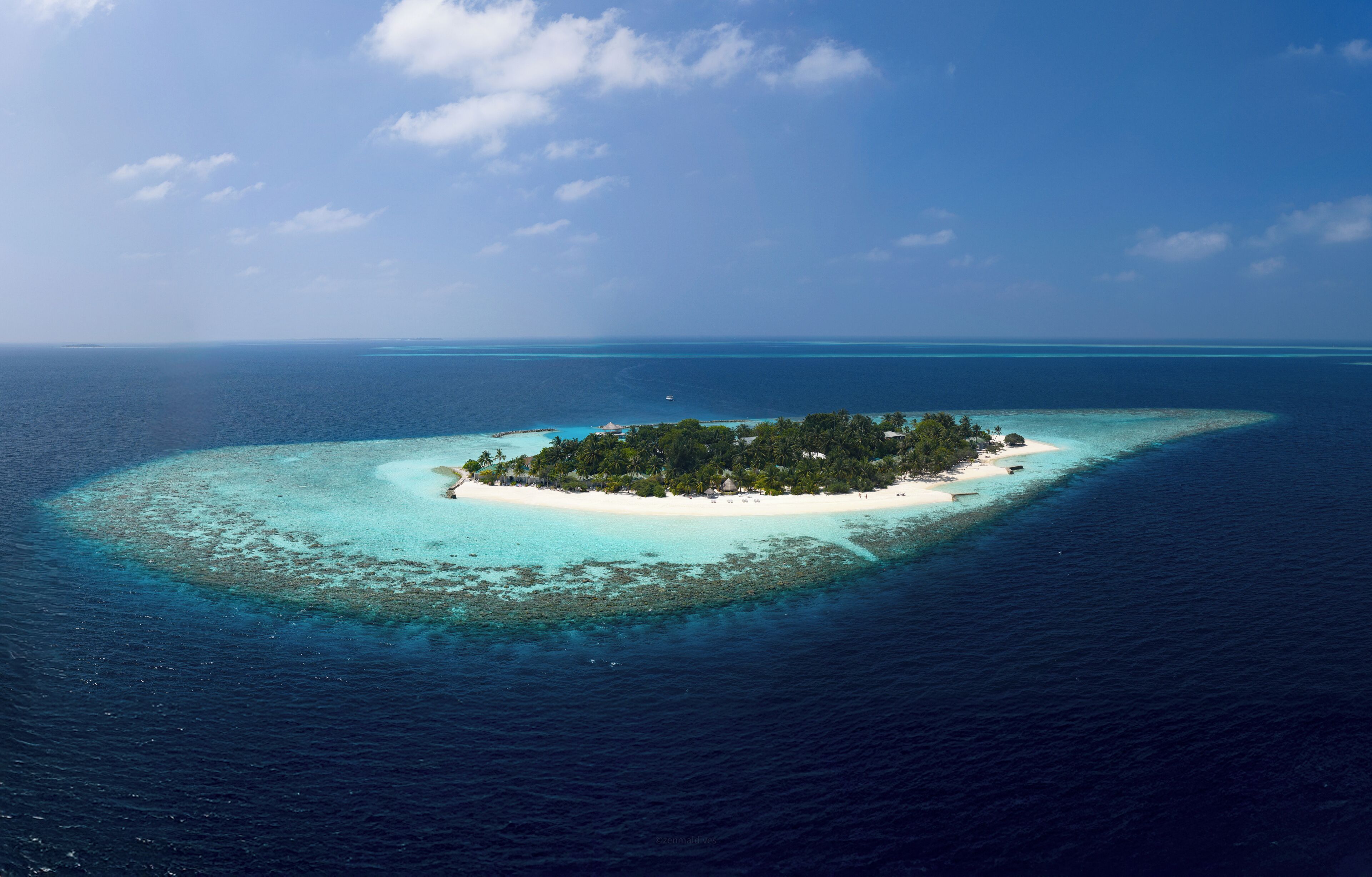 Vue aérienne d’une petite île dotée d’une plage de sable blanc et d’une végétation luxuriante.