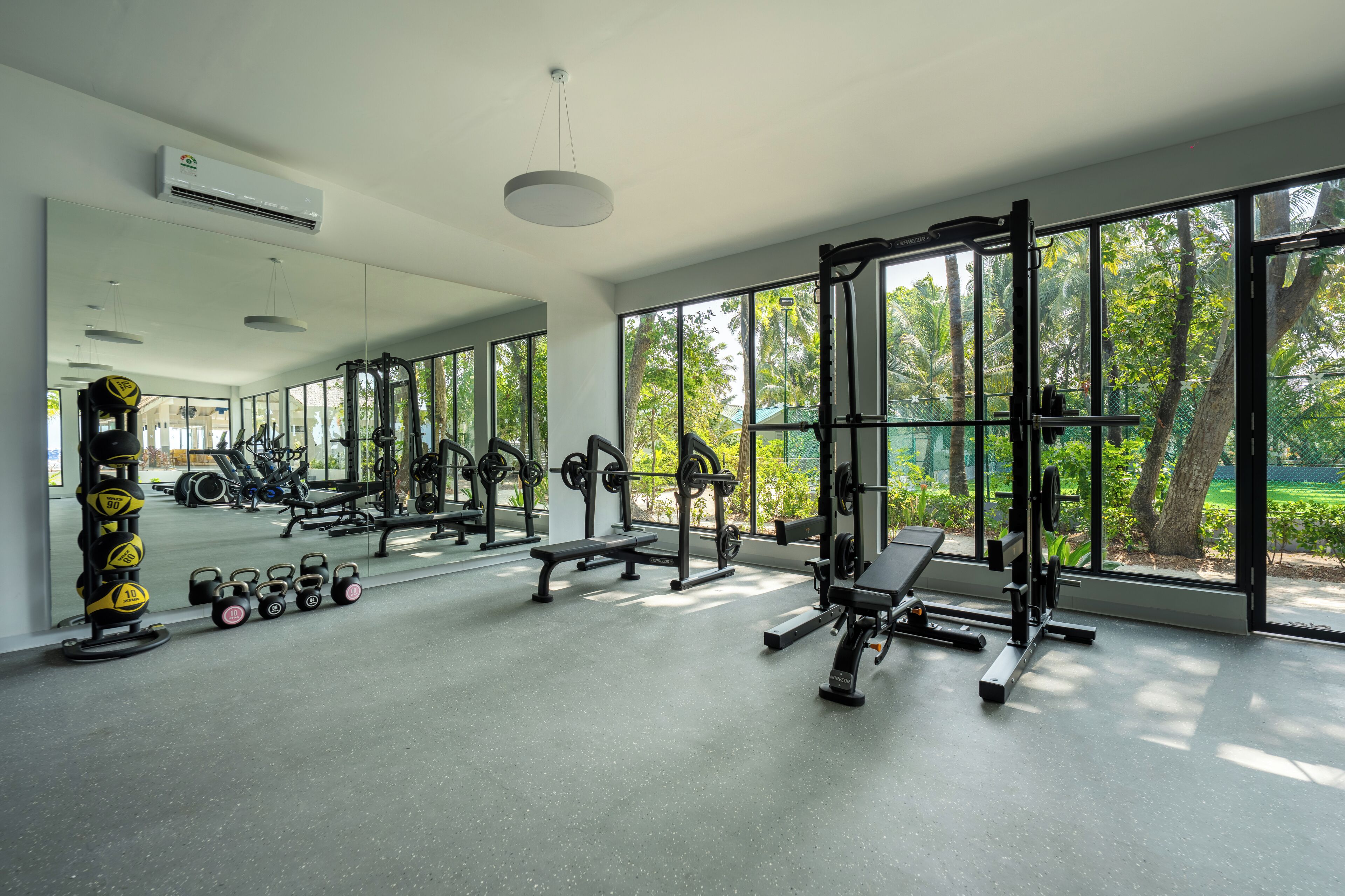 A gym with exercise equipment, large windows, and a view of greenery.