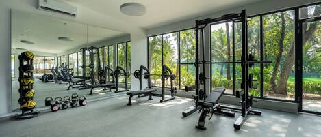 A gym with exercise equipment, large windows, and a view of greenery.