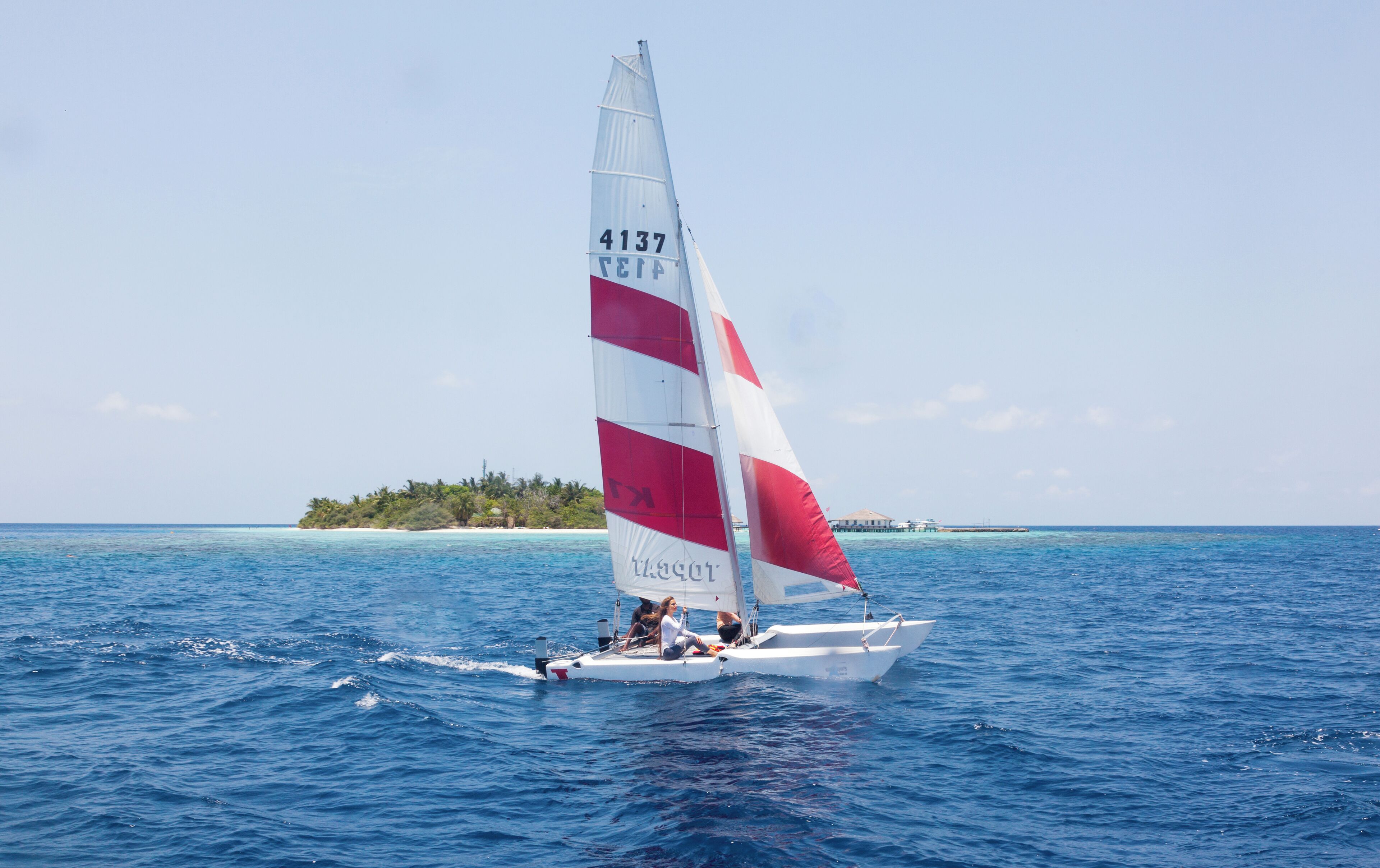 Un velero con vela roja y blanca, número 4137, en el agua.