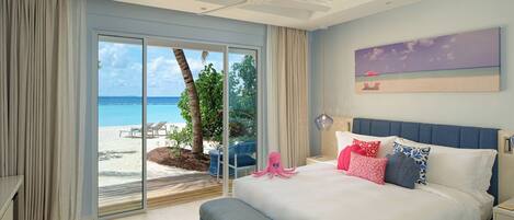 A bedroom with a large bed, a bench, a desk, and a view of the beach.