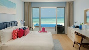 Een hotelkamer met een bed, een bureau en uitzicht op zee.