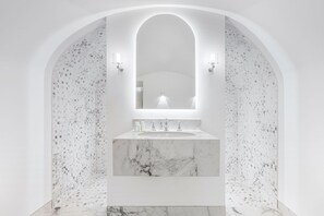 A modern bathroom with a marble sink, two wall-mounted lights, and a large mirror.