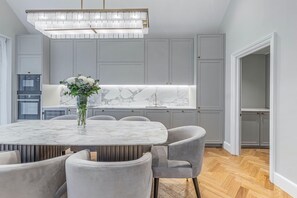 A modern kitchen with a marble countertop, grey cabinets, and a dining area with a marble table and grey chairs.