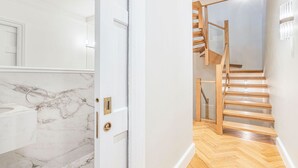 A modern interior with a marble bathroom, wooden staircase, and a view of the sky. - Wimpole Mews - 4 Bedroom Apartment (London)