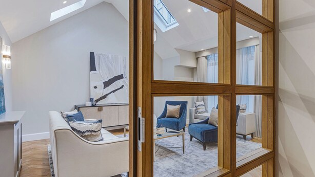 A modern living room with a large mirror, a sofa, a chair, and a painting on the wall. - Wimpole Mews - 4 Bedroom Apartment (London)