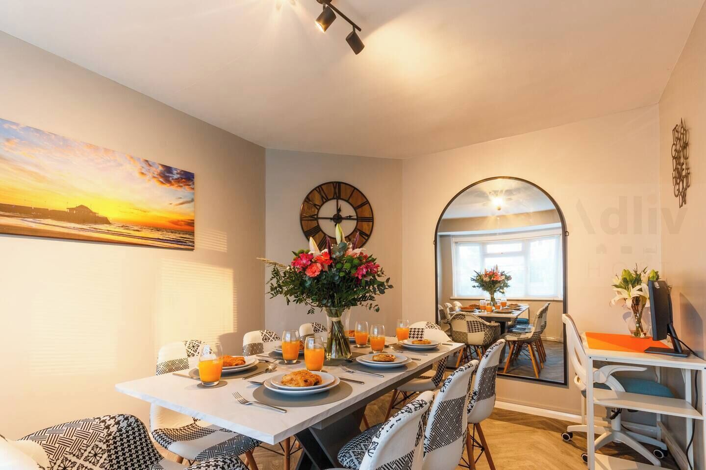 Gather for meals in this elegant dining space, featuring a designer table set for six, a statement wall clock, and a vibrant floral centrepiece. A welcoming space for breakfast, dinner or even remote working.