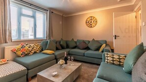 A living room with a sectional sofa, a coffee table, and a wall clock. - Pet-Friendly Coastal Home for 6 by Adliv (Broadstairs)