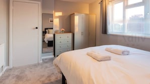A bedroom with a bed, a dresser, a wardrobe, and a window with blinds. - Pet-Friendly Coastal Home for 6 by Adliv (Broadstairs)