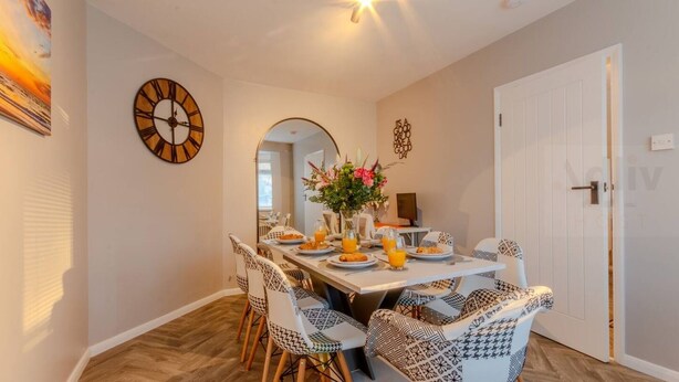 A dining area with a round table, patterned chairs, and a clock on the wall. - Pet-Friendly Coastal Home for 6 by Adliv (Broadstairs)