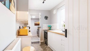 A modern kitchen with white cabinets, a wooden countertop, and a yellow appliance. - Pet-Friendly Coastal Home for 6 by Adliv (Broadstairs)