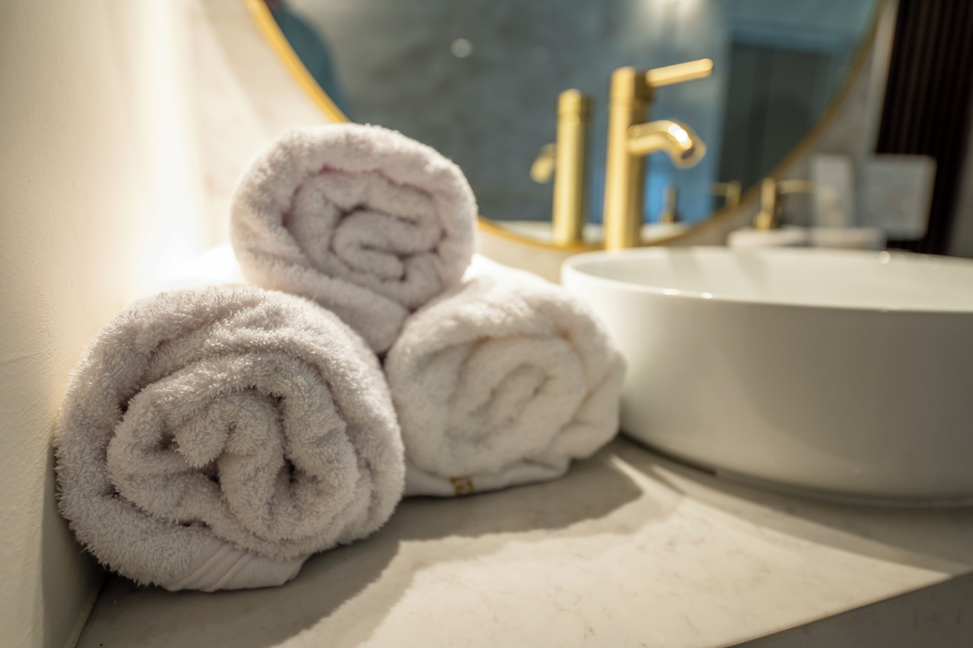 Une salle de bain avec un lavabo blanc et un miroir doté d’un cadre doré.