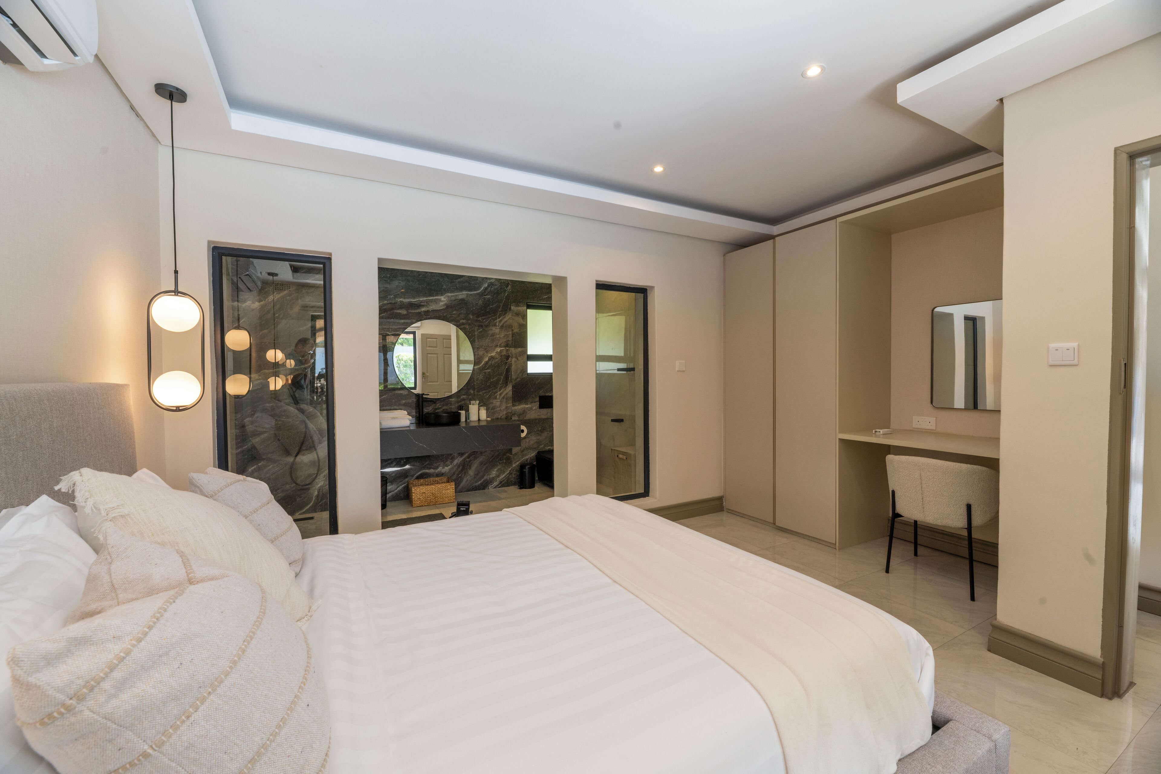 A modern bedroom with a large bed, a desk, and a mirror.