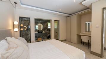 A modern bedroom with a large bed, a desk, and a mirror.