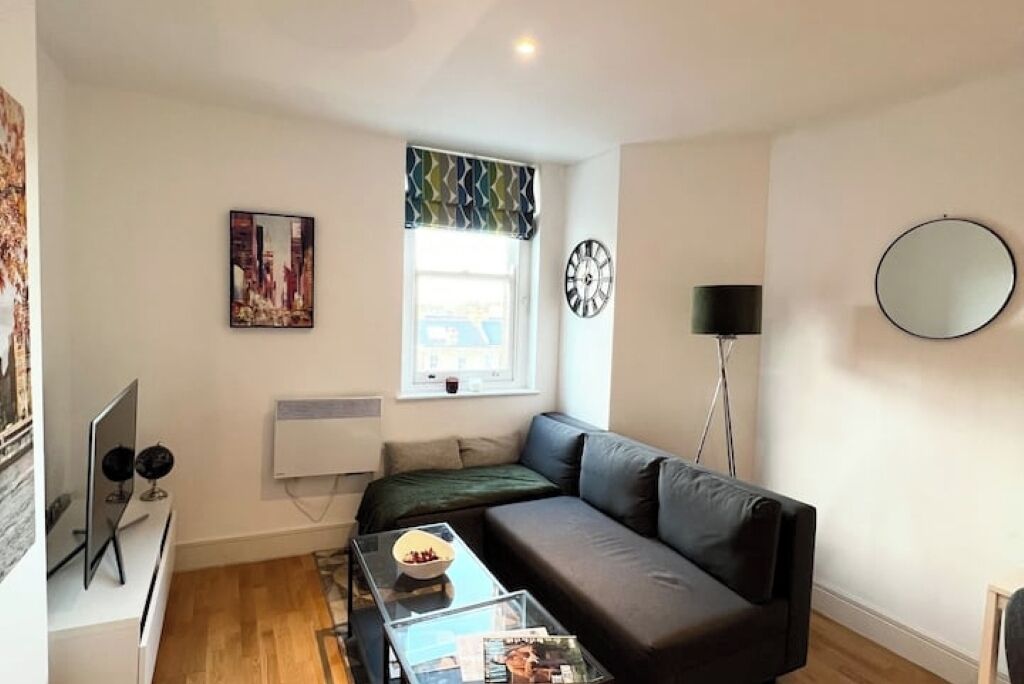A modern living room with a sofa, a coffee table, a TV, and a painting on the wall.