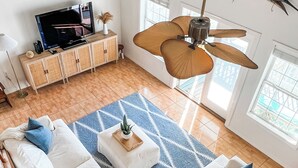 En rummelig stue med en stor sofa, et sofabord og en ventilator i loftet.