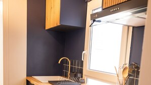 A compact kitchen with a wooden countertop, a built-in oven, and a window above the sink. - The Royal Hues (Reims)