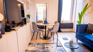 A compact living space with a dining area, a sofa, and a coffee table. - The Royal Hues (Reims)