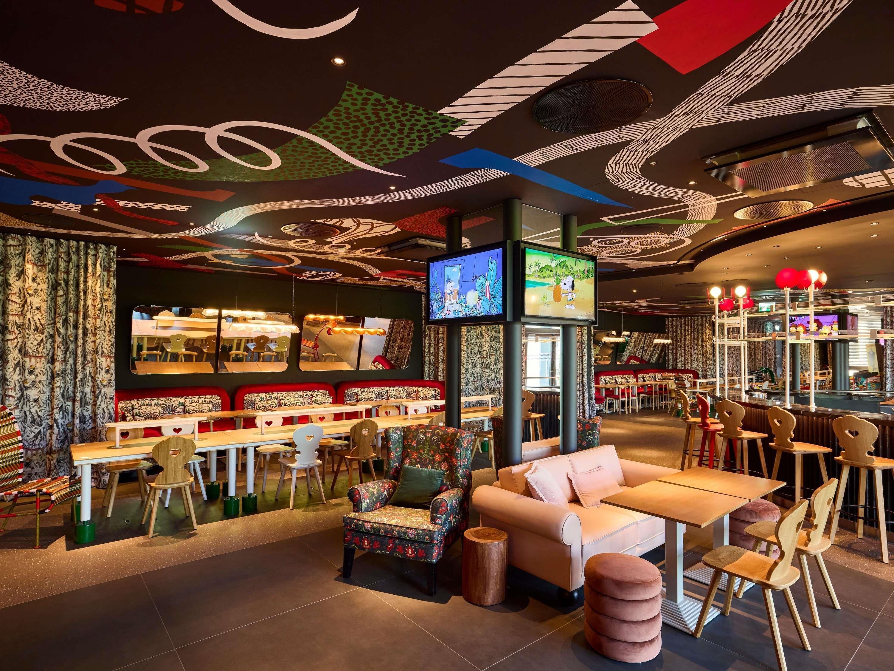 A restaurant interior with a bar area, seating arrangements, and a television screen.