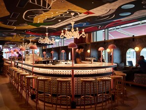 A bar area with a round counter, stools, and a ceiling with abstract designs. - Mama Shelter Zurich (Zurich)
