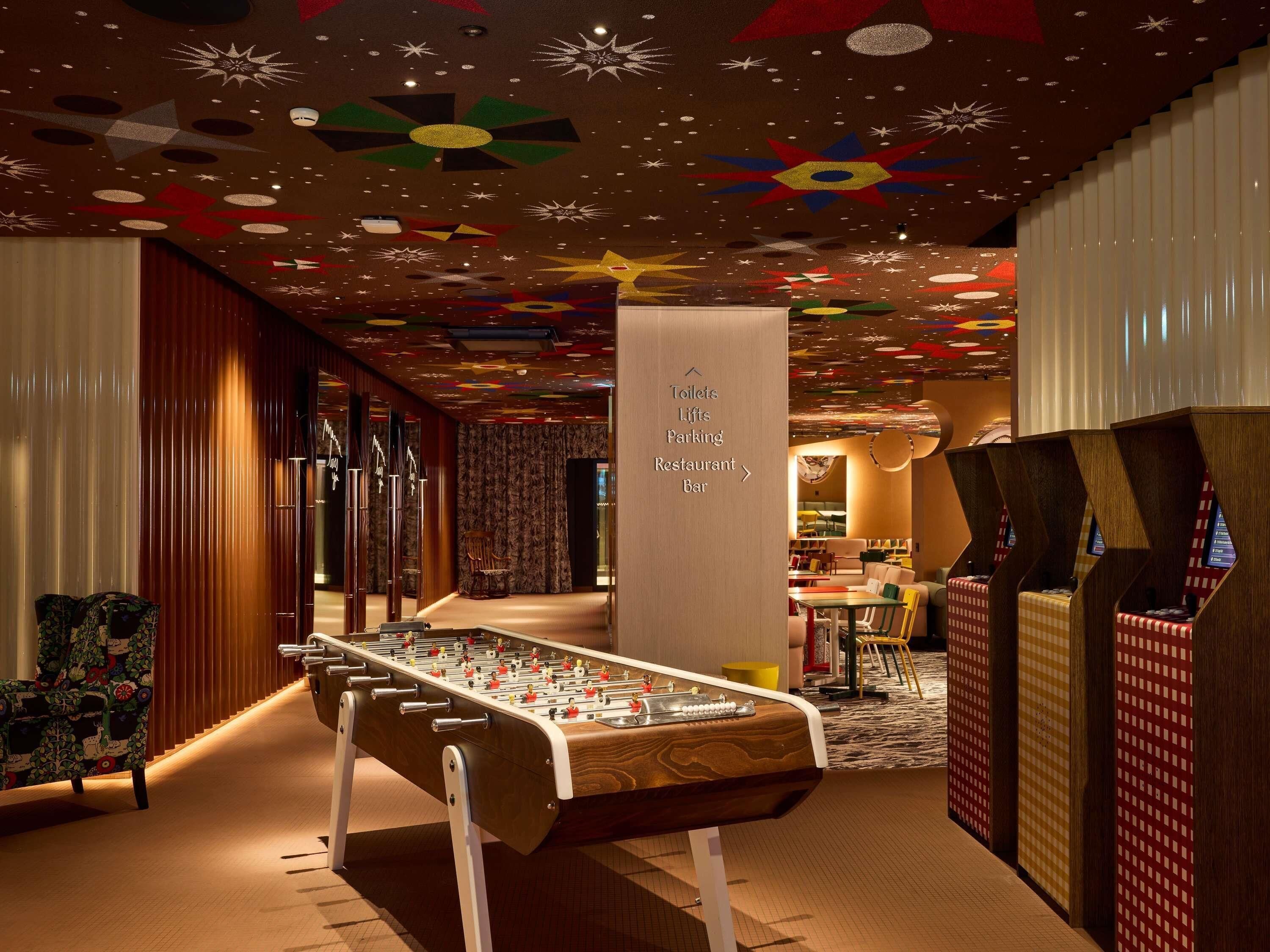 A hotel lobby with a foosball table, a bar, and a restaurant.
