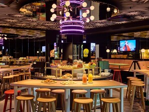A modern restaurant with a central bar area, multiple seating options, and a ceiling with a unique light fixture.