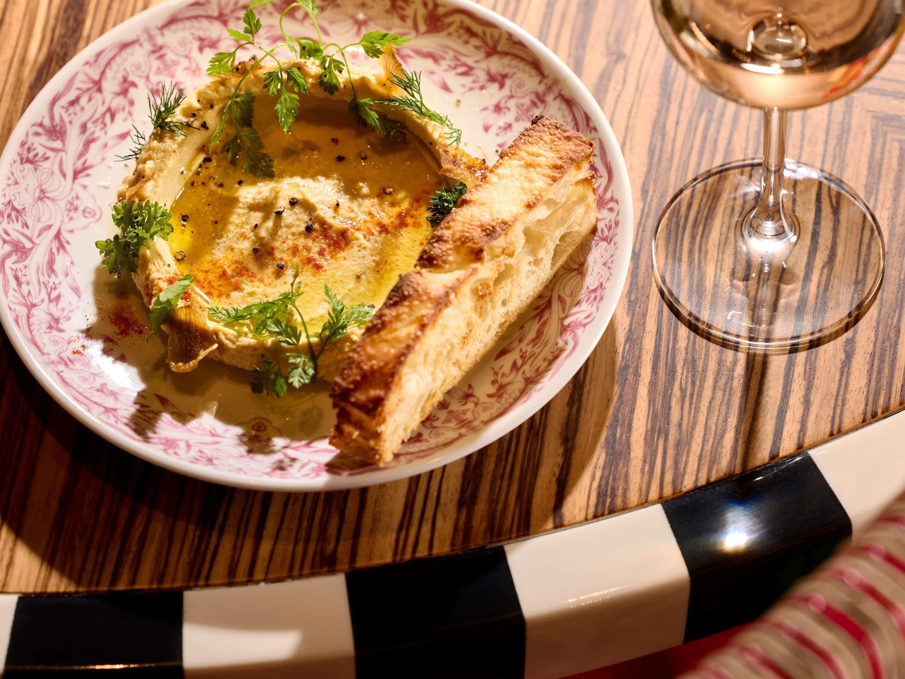 A plate with a food item, a glass of wine, and a table with a striped pattern.