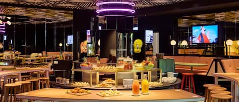 Un restaurante moderno con barra central, diversas opciones de asientos y una variedad de exhibiciones de comida y bebidas.