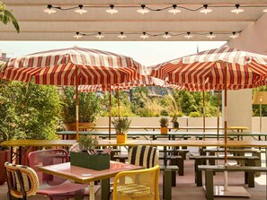 An outdoor seating area with striped umbrellas, tables, and chairs. - Mama Shelter Zurich (Zurich)