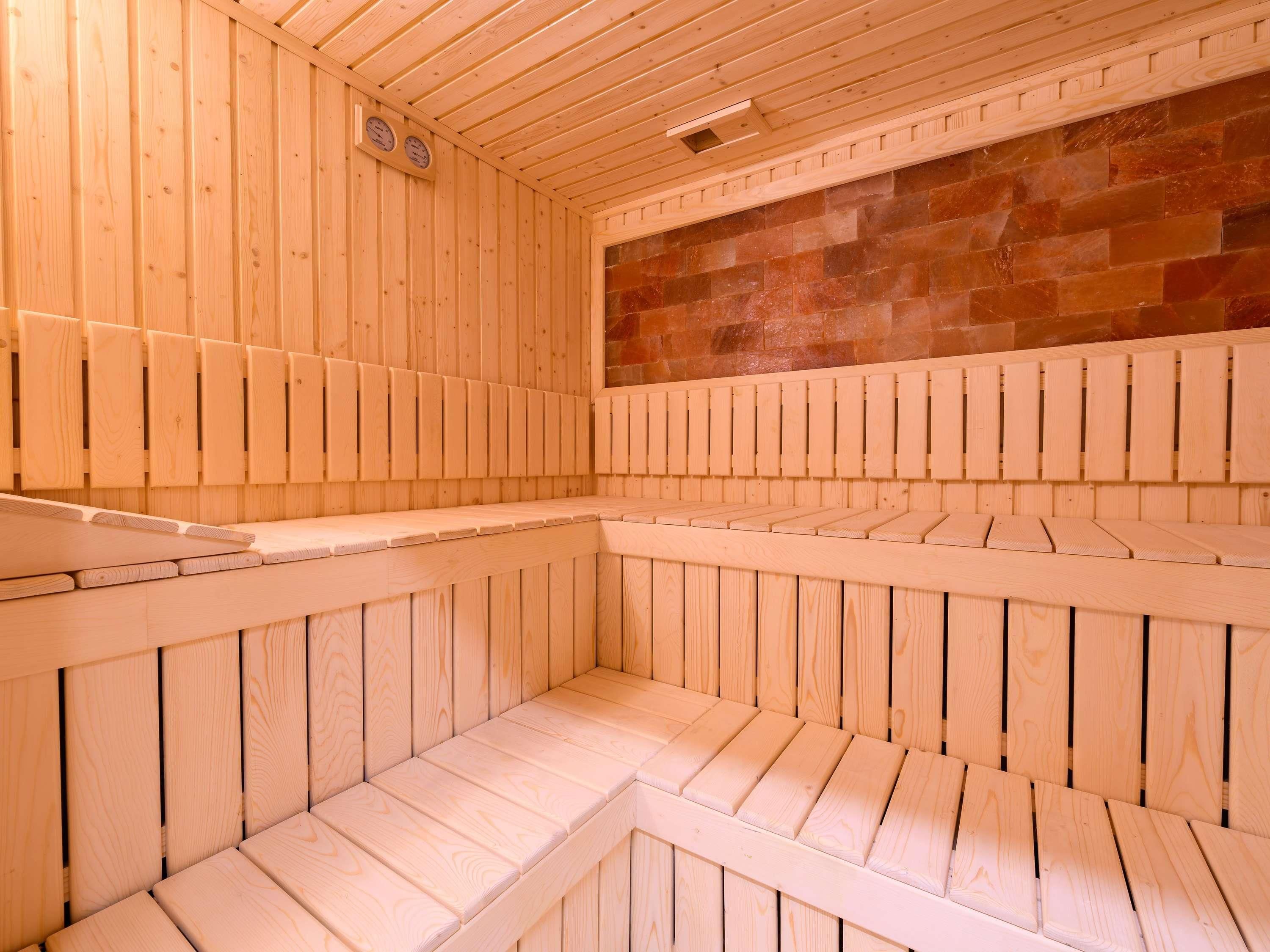 A sauna with wooden benches and a stone wall.