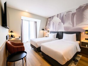 A hotel room with two beds, a desk, a chair, a TV, and a large abstract mural on the wall. - Mercure Alba Iulia (Alba Iulia)
