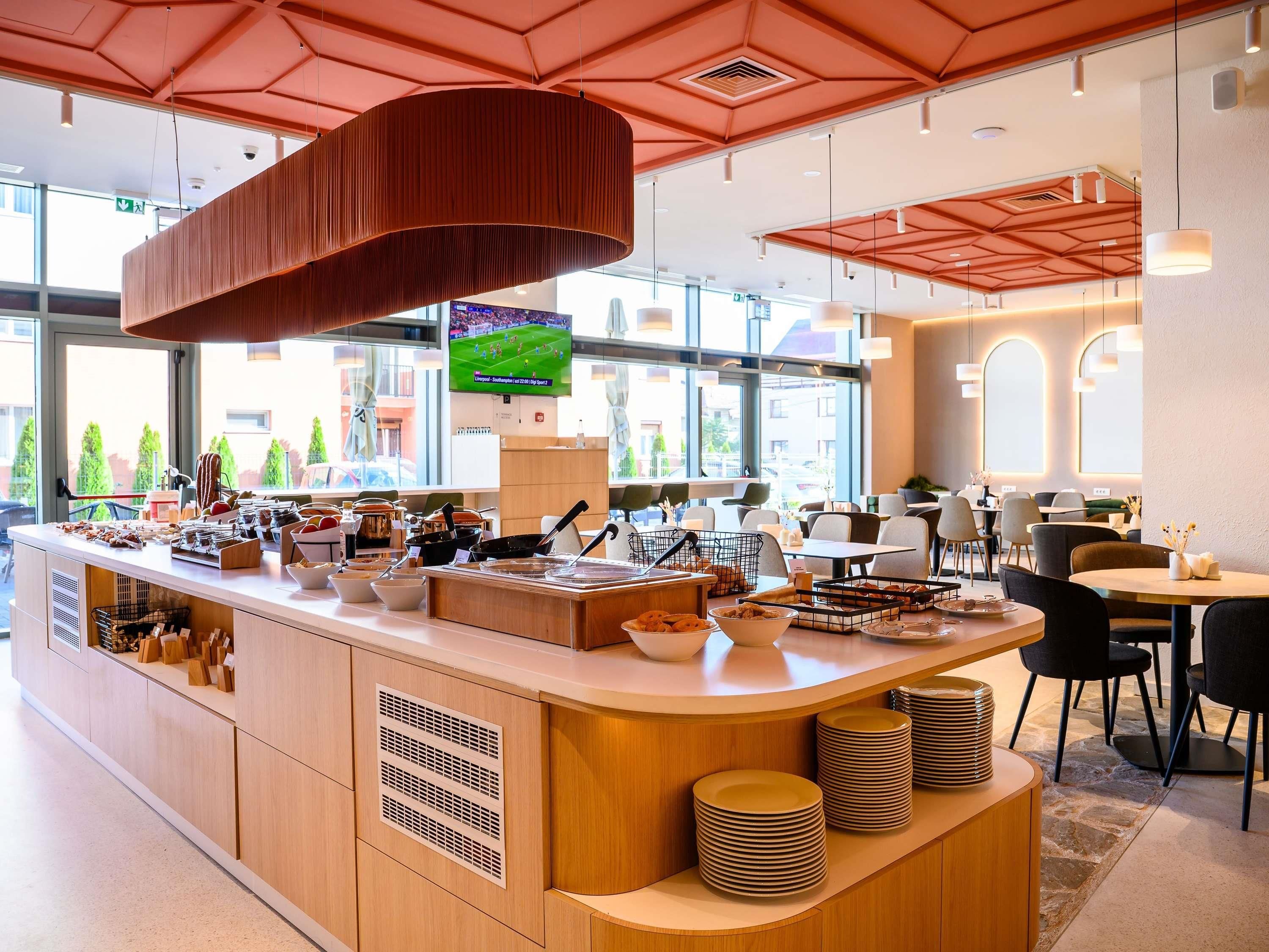Un restaurante moderno con una barra central, zona de estar y grandes ventanales.