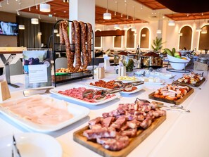 A buffet with various meats and cheeses, including cured meats and sliced ham. - Mercure Alba Iulia (Alba Iulia)