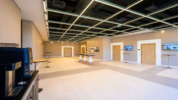A spacious lobby with a modern ceiling design, a reception area, and a television screen.