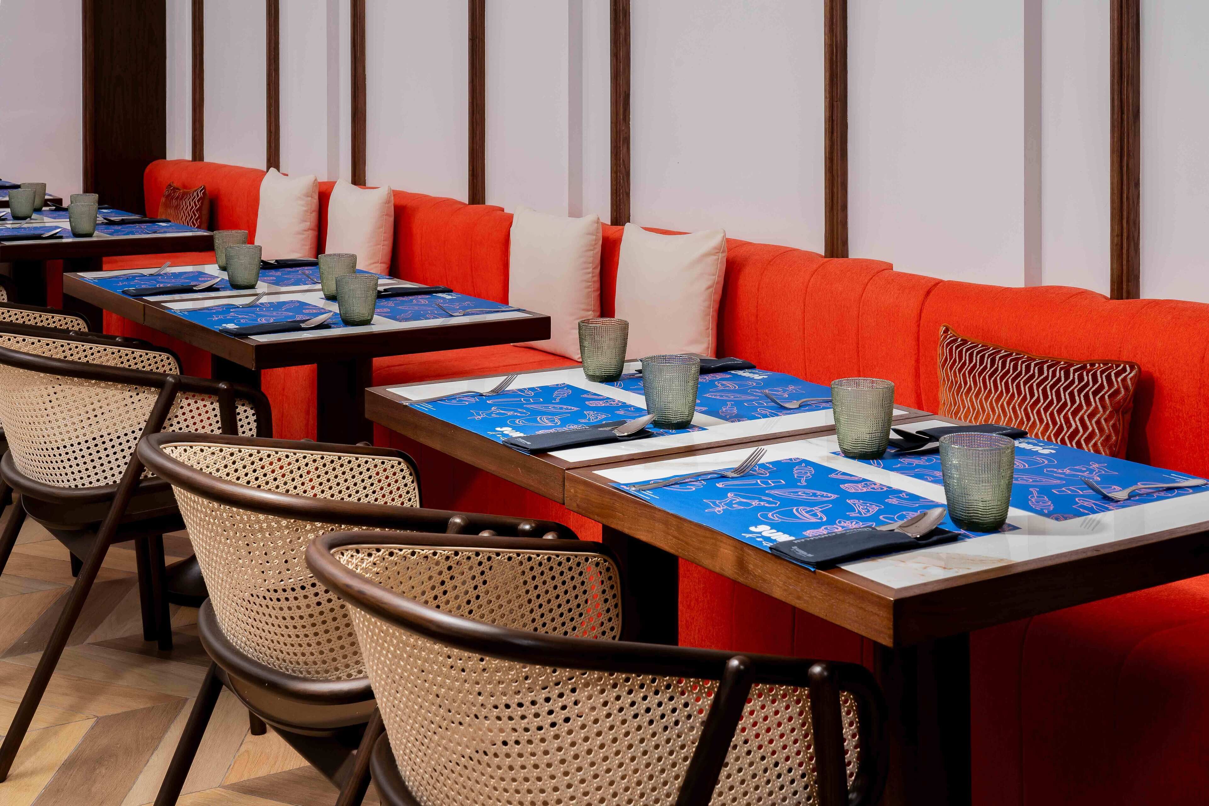 Een restaurant met meerdere tafels, elk met een blauwe tafelkleed en een groen glas.
