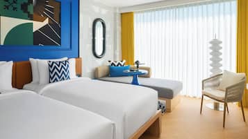 Ein Hotelzimmer mit zwei Betten, einem Schlafsofa, einem kleinen Tisch und einem Stuhl.