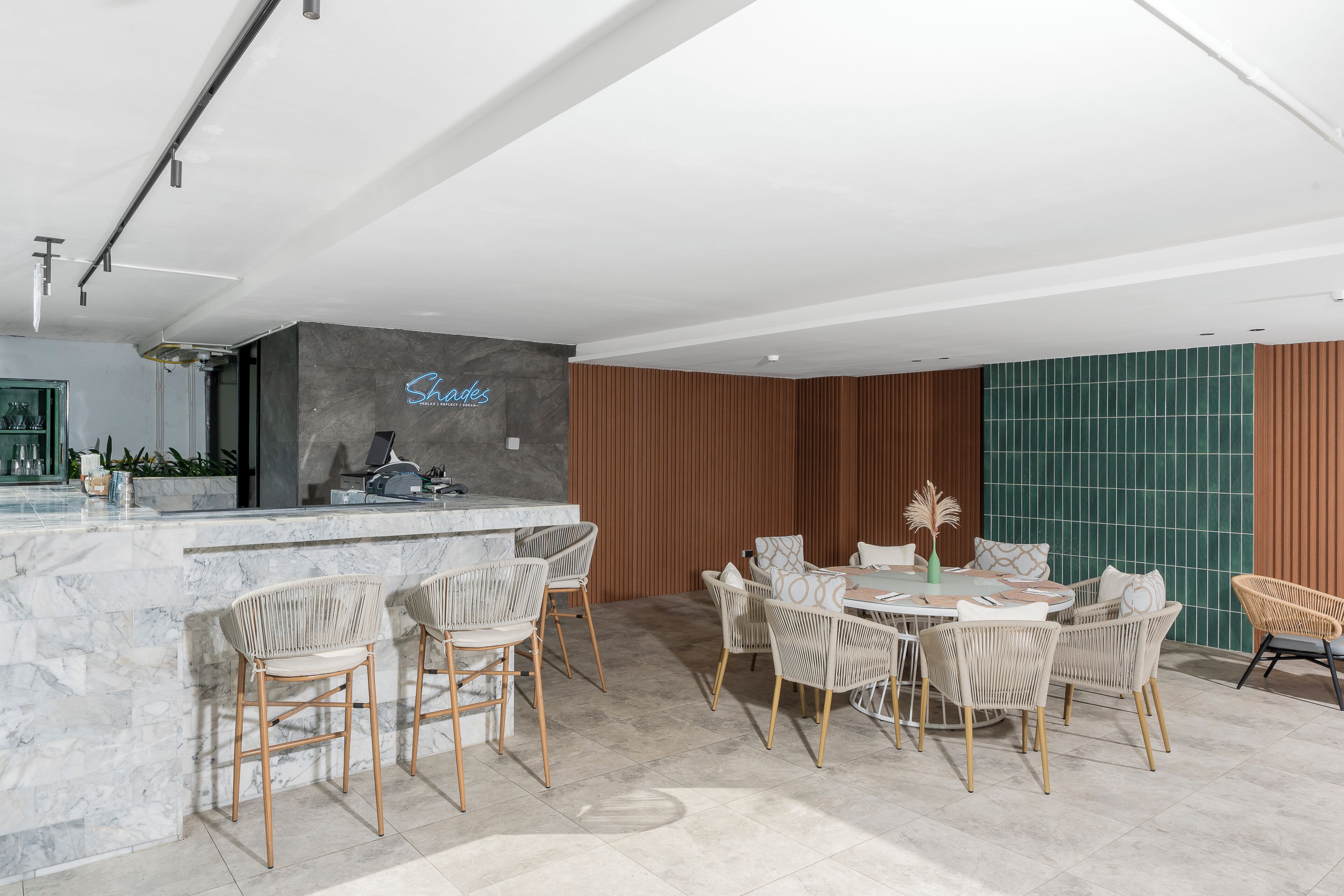 Une cuisine moderne dotée d’un plan de travail en marbre, d’une cuisinière encastrée et d’un coin bar avec des chaises en osier.