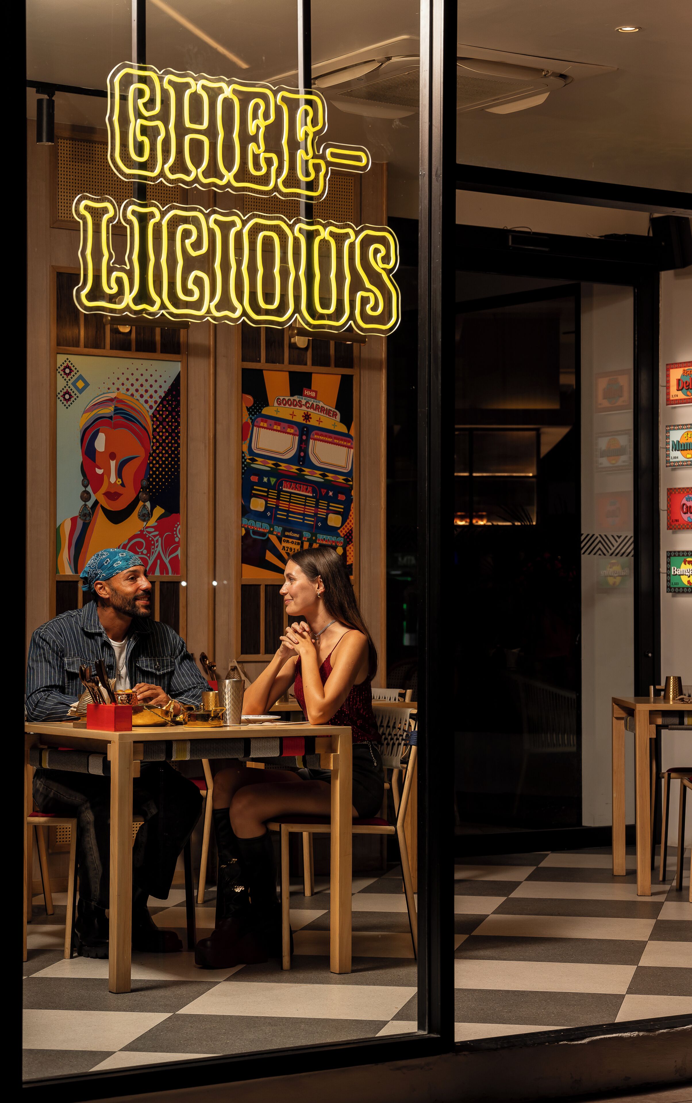 A restaurant with a checkered floor, a neon sign reading 'CHIP LIOUS,' and a colorful mural on the wall.