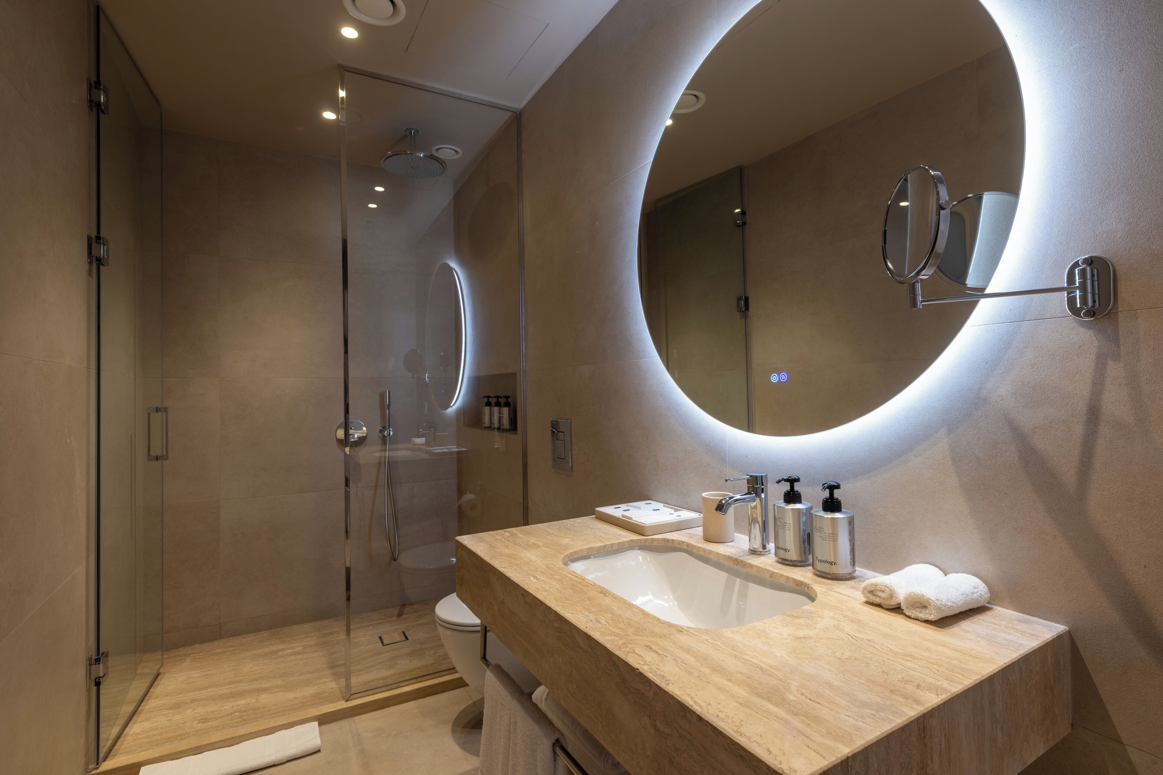 A modern bathroom with a glass shower enclosure, a sink with a vanity, and a large mirror.