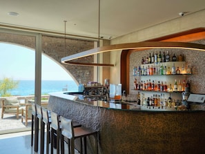 A bar with a stone wall and a view of the sea. - Green Coast Hotel Mgallery Collection (Himare)